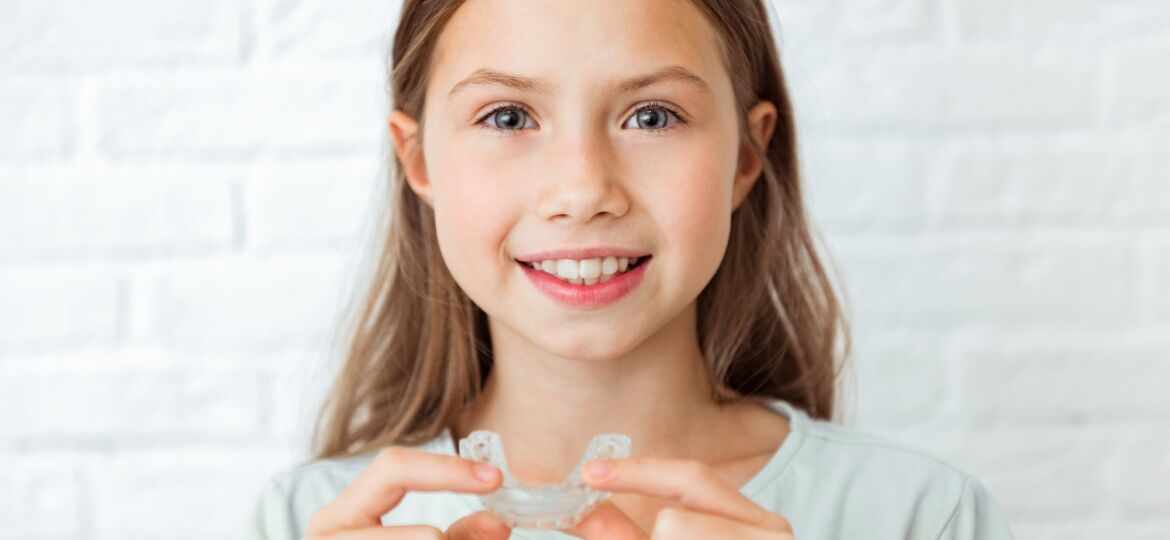 Smiling child girl with perfect and healthy teeth using removable braces or aligner